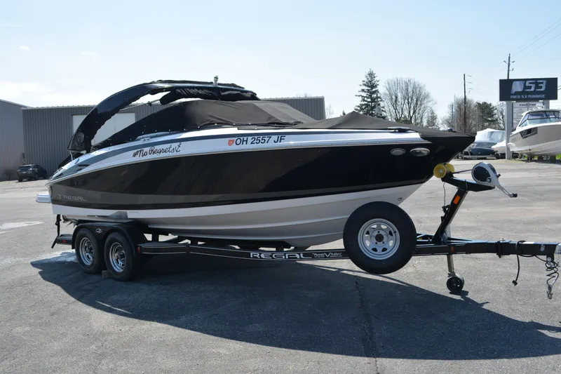 The Image of 2014 Regal 2300 Bowrider boat on trailer, black cover, parked outdoors. - 0