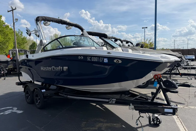 Slide: The Image of 2023 MasterCraft XT20 boat on trailer under a clear blue sky. - 1