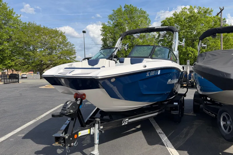 Slide: The Image of 2023 MasterCraft XT20 boat on trailer in parking lot, sunny day. - 2