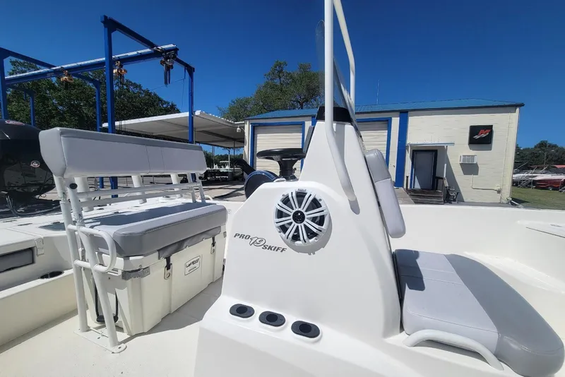Slide: The Image of 2025 Mako Pro Skiff 19 CC boat interior with seating and storage, under clear blue sky. - 10