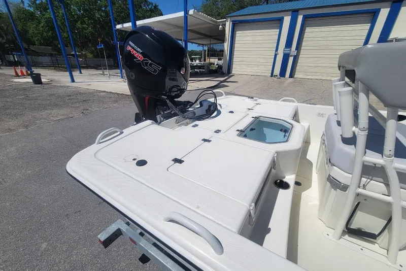 Slide: The Image of 2025 Mako Pro Skiff 19 CC boat with powerful outboard motor in a marina setting. - 12
