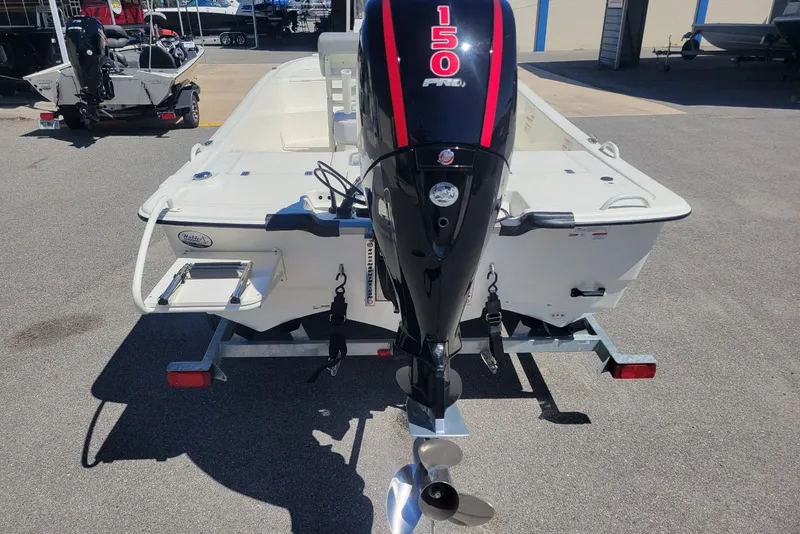 Slide: The Image of 2025 Mako Pro Skiff 19 CC with 150 HP engine on trailer, rear view. - 3