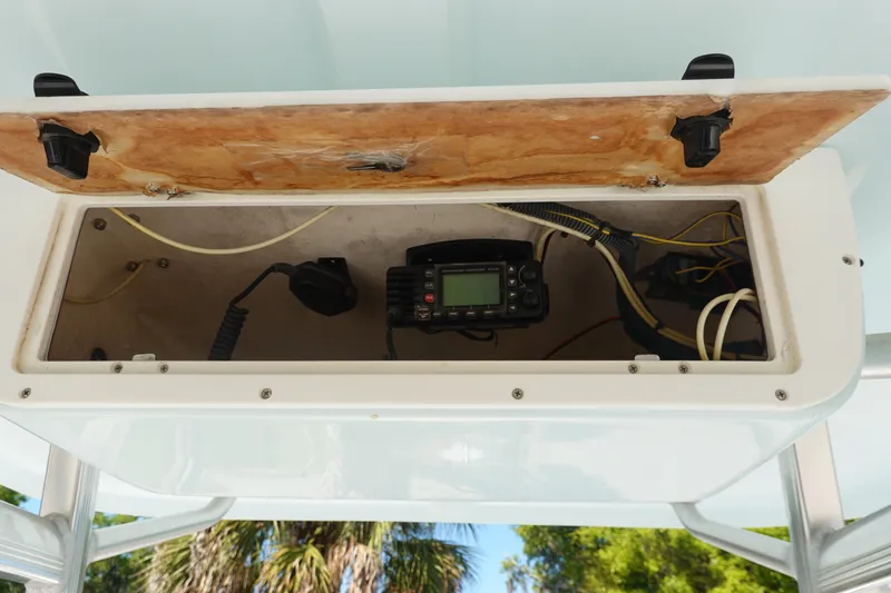 Slide: The Image of Open storage compartment on 2014 Sea Hunt Ultra 225 boat, revealing electronic equipment and wiring. - 21
