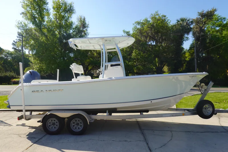 Slide: The Image of 2014 Sea Hunt Ultra 225 boat on trailer, parked outdoors with trees in background. - 4