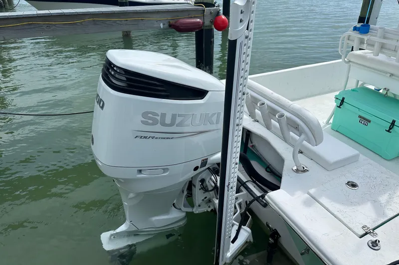 Slide: The Image of 2023 Blazer Bay 2400 boat with Suzuki outboard motor, docked on calm water. - 18