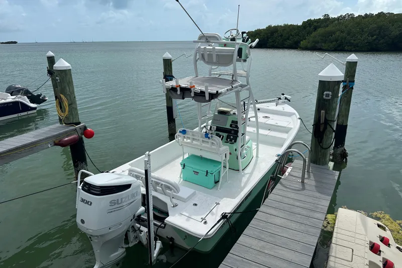 Slide: The Image of 2023 Blazer Bay 2400 boat docked, featuring a Suzuki 300 engine, in a serene marina setting. - 20
