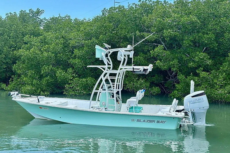 Slide: The Image of 2023 Blazer Bay 2400 boat with Suzuki engine on calm water, surrounded by lush greenery. - 22