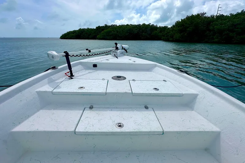 Slide: The Image of 2023 Blazer Bay 2400 boat on calm water, featuring a spacious deck and lush shoreline. - 34