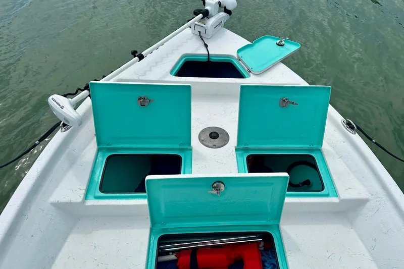 Slide: The Image of 2023 Blazer Bay 2400 boat with open storage compartments on calm water. - 36