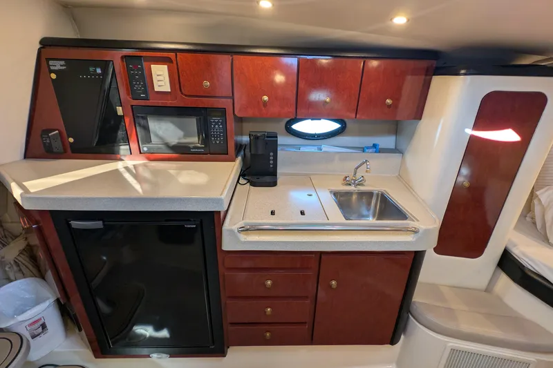 Slide: The Image of 2001 Wellcraft 3300 Martinique yacht kitchen with sink, microwave, and wooden cabinets. - 47