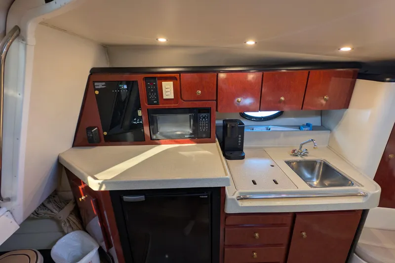 Slide: The Image of 2001 Wellcraft 3300 Martinique yacht kitchen with sink, microwave, and wooden cabinets. - 48