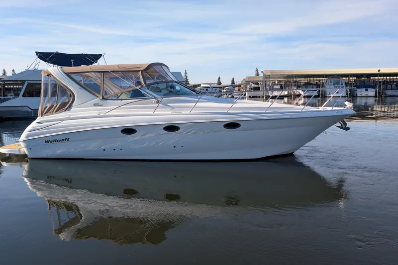Slide: The Image of 2001 Wellcraft 3300 Martinique boat docked in a marina, reflecting on calm water. - 5