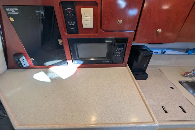 Slide: The Image of 2001 Wellcraft 3300 Martinique kitchen area with microwave, wooden cabinets, and countertop. - 57