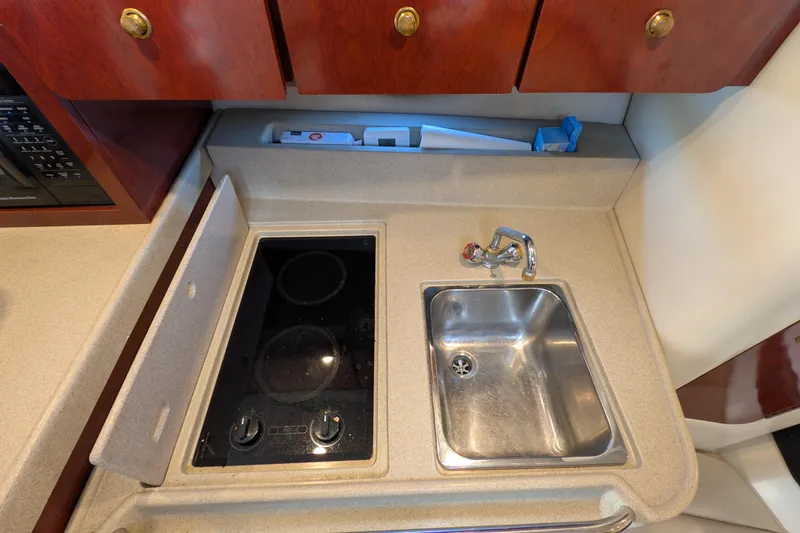 Slide: The Image of 2001 Wellcraft 3300 Martinique kitchen with stove and sink, featuring wooden cabinets. - 59