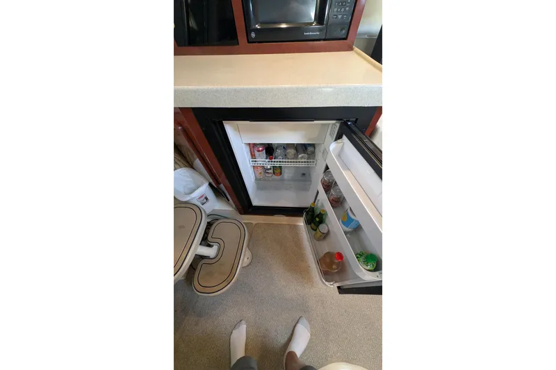 Slide: The Image of Interior of 2001 Wellcraft 3300 Martinique showing open fridge with beverages and microwave. - 64