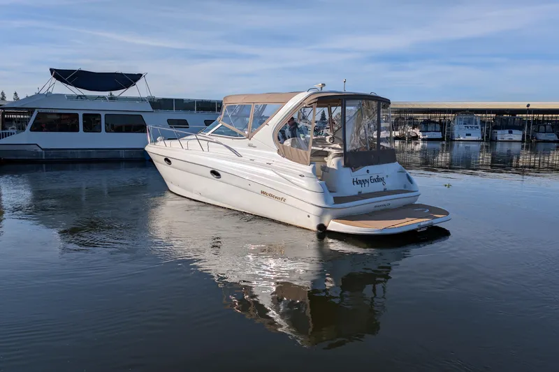 Slide: The Image of 2001 Wellcraft 3300 Martinique boat docked in a marina, reflecting on calm water. - 9