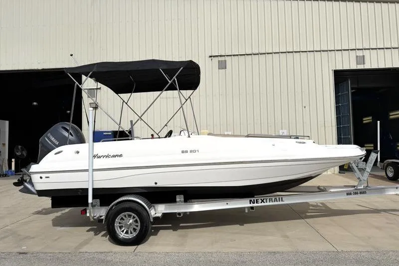 The Image of 2023 Hurricane SunDeck Sport 201 OB boat on trailer, parked outside a warehouse. - 0