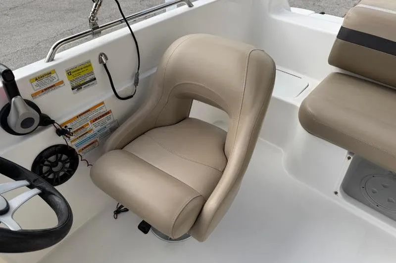 Slide: The Image of 2023 Hurricane SunDeck Sport 201 OB boat interior with beige captain's chair and steering wheel. - 19
