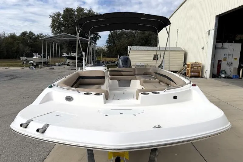 Slide: The Image of 2023 Hurricane SunDeck Sport 201 OB boat with canopy, docked near a warehouse. - 5