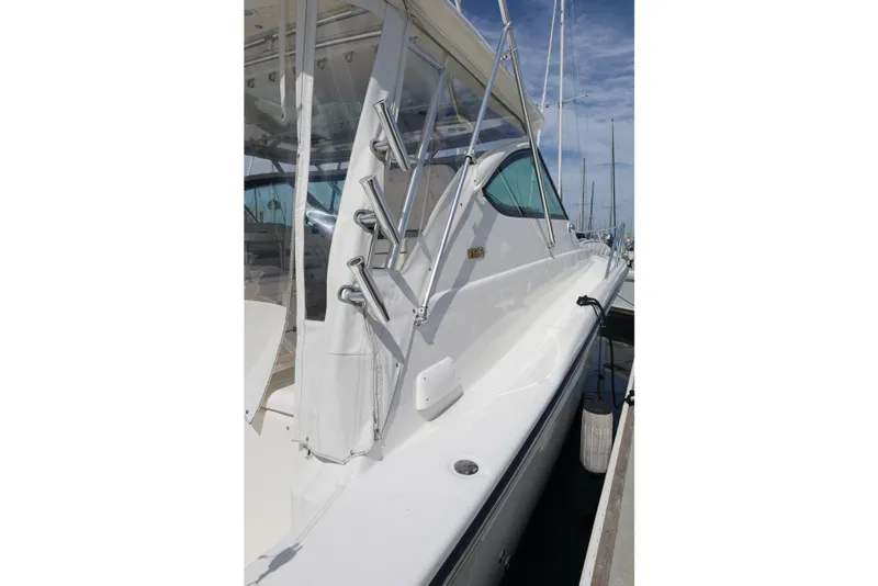 Slide: The Image of 2007 Tiara 4200 Open yacht docked, showcasing sleek white exterior and fishing rod holders. - 9