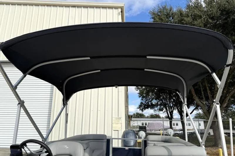 Slide: The Image of 2023 Bennington 22SSR boat with black canopy, parked near a building. - 29
