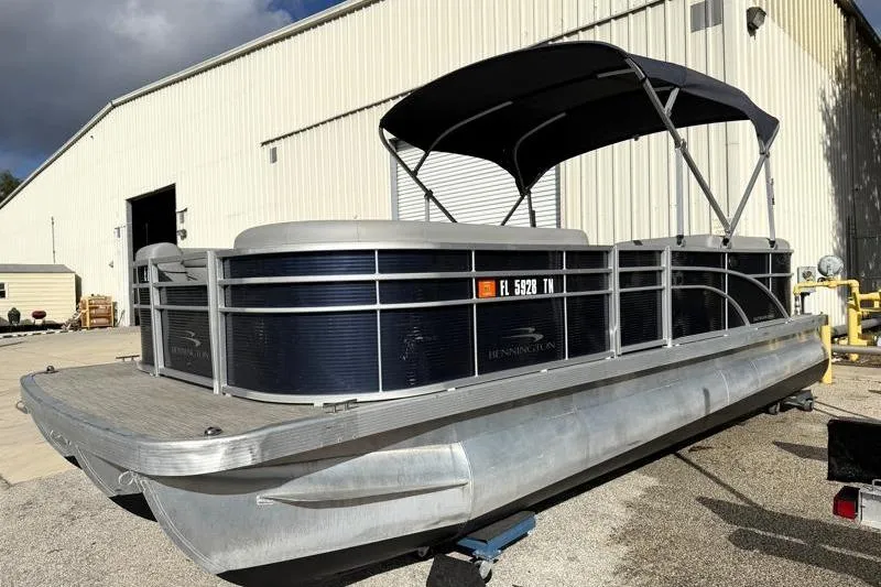 Slide: The Image of 2023 Bennington 22SSR pontoon boat with canopy, parked outside a warehouse. - 3