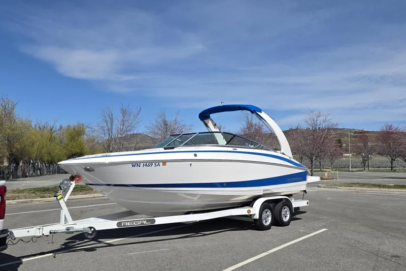 The Image of 2013 Regal 2500 Bowrider boat on trailer in parking lot under clear sky. - 0