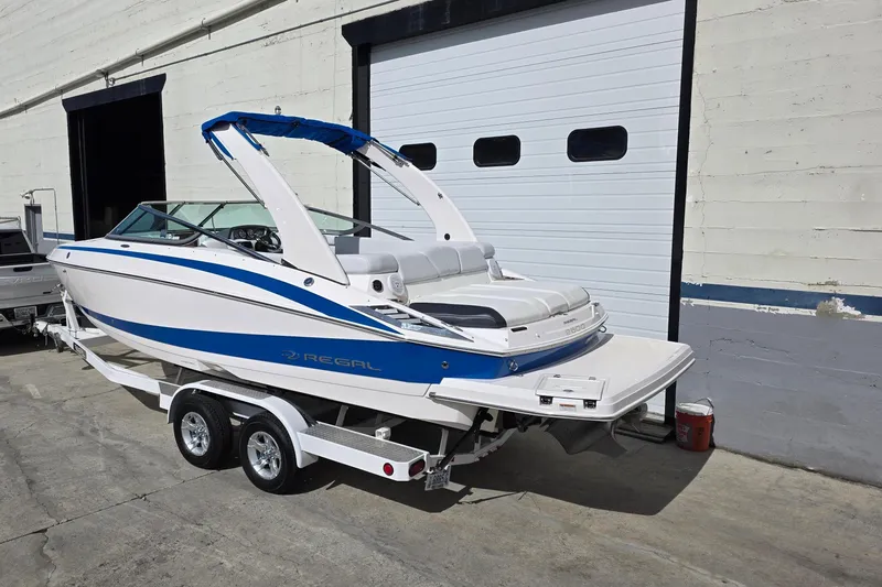 Slide: The Image of 2013 Regal 2500 Bowrider boat on trailer, parked outside a garage. - 2