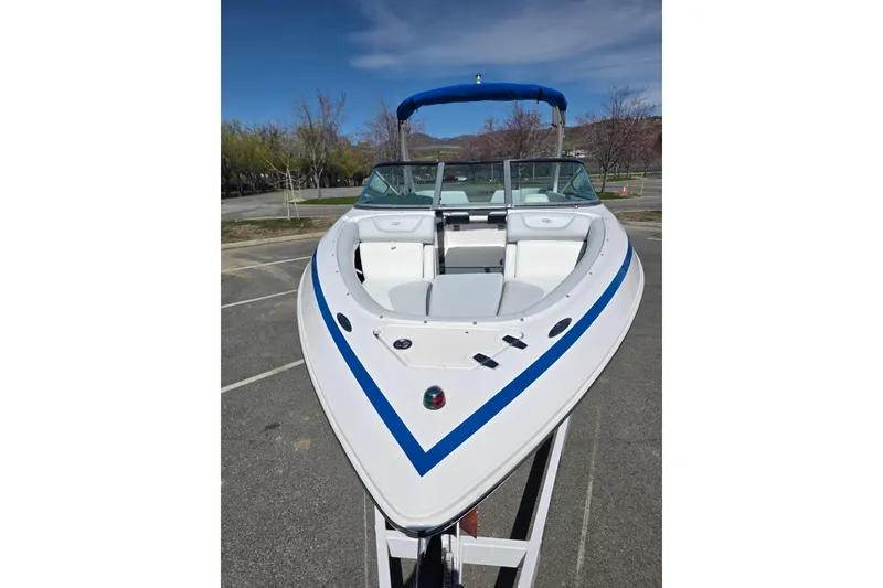 Slide: The Image of 2013 Regal 2500 Bowrider boat with blue stripe, parked outdoors under clear sky. - 25