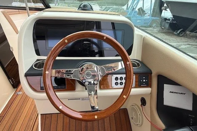 Slide: The Image of 2023 Chris-Craft Calypso 28 dashboard with wooden steering wheel and modern controls. - 13