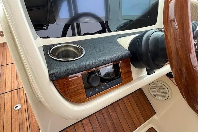 Slide: The Image of 2023 Chris-Craft Calypso 28 dashboard with wood accents, steering wheel, and cup holder. - 15