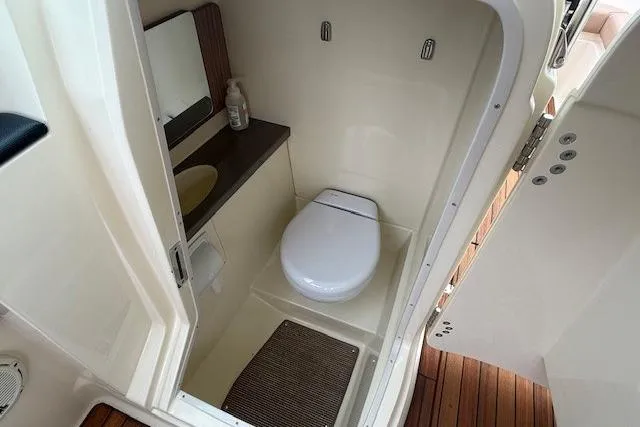 Slide: The Image of 2023 Chris-Craft Calypso 28 boat bathroom with toilet, sink, and wooden flooring. - 18