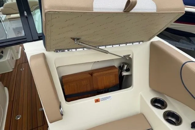 Slide: The Image of 2023 Chris-Craft Calypso 28 boat interior storage compartment with beige upholstery and cup holders. - 27