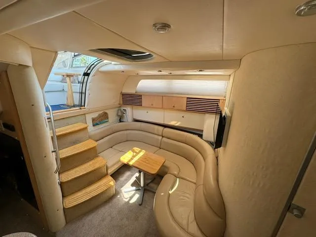 Slide: The Image of 1998 Bayliner 4085 Avanti Sunbridge interior with beige seating, wooden table, and steps. - 13