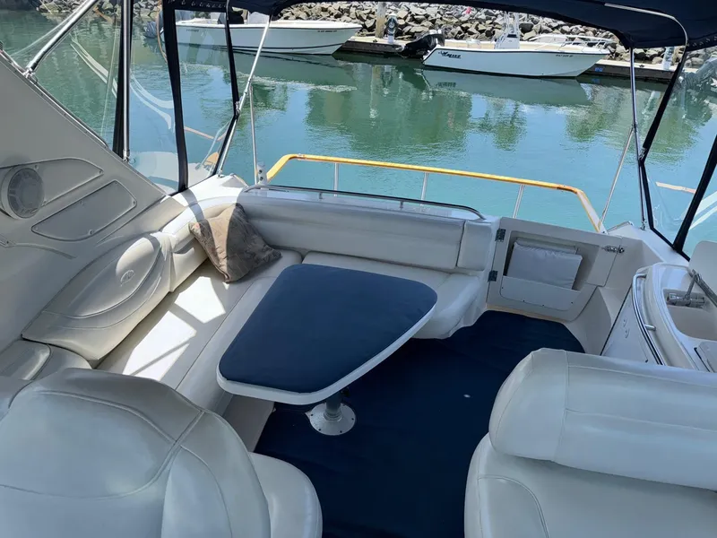 Slide: The Image of 1998 Bayliner 4085 Avanti Sunbridge interior with white seating and blue table, docked by water. - 31