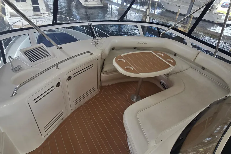 Slide: The Image of 2004 Sea Ray 480 Sedan Bridge yacht interior with seating and table, docked at marina. - 3