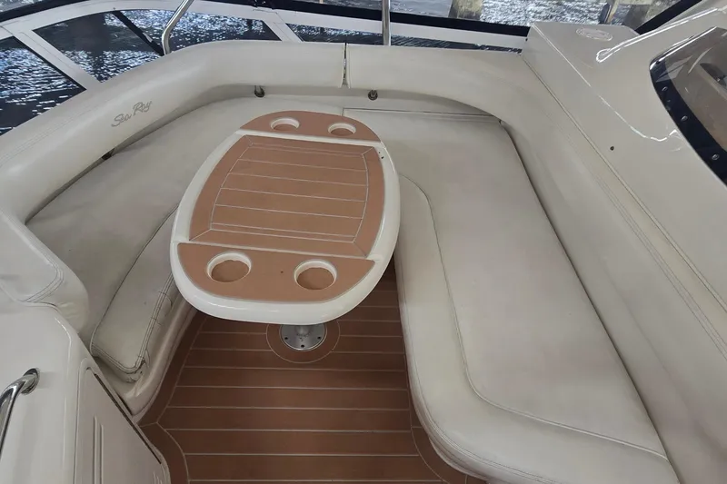 Slide: The Image of 2004 Sea Ray 480 Sedan Bridge interior with cushioned seating and a wooden table. - 4