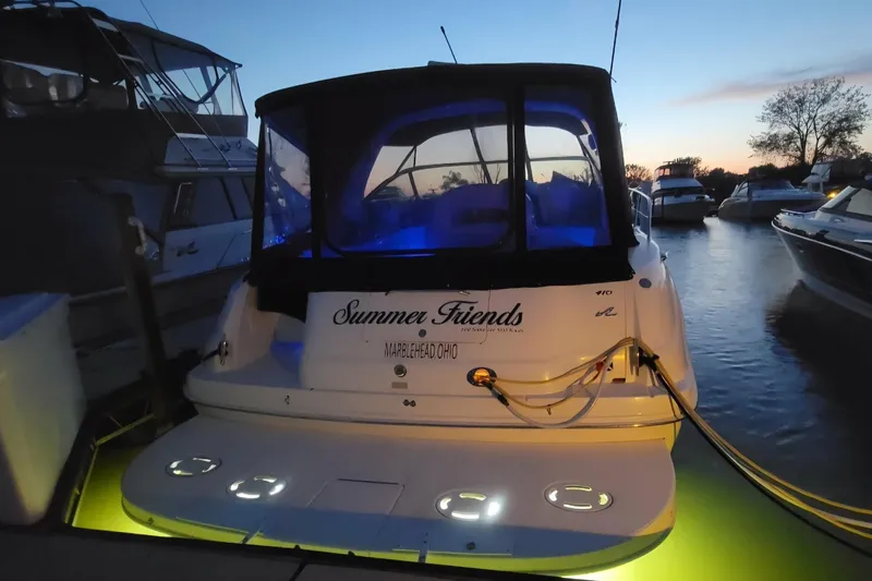 Slide: The Image of 2002 Sea Ray 410 Sundancer docked at sunset with illuminated deck and blue canopy. - 2
