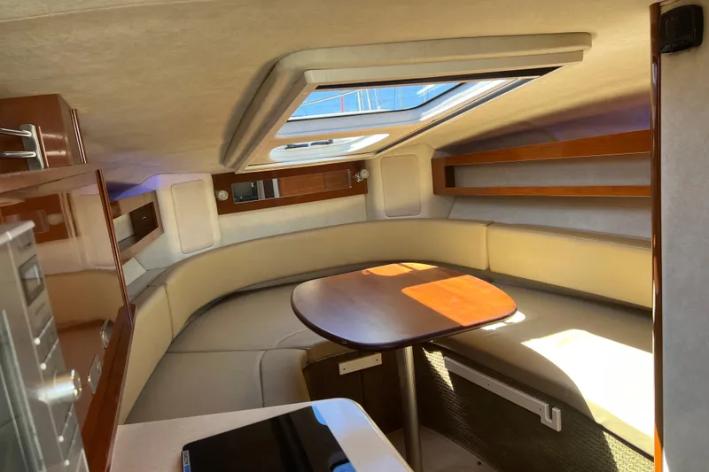 Slide: The Image of Interior of 2013 Sea Ray Sundancer 280, featuring a cozy seating area with a wooden table. - 18