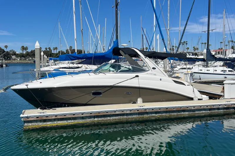 Slide: The Image of 2013 Sea Ray Sundancer 280 docked at a marina with sailboats in the background. - 2