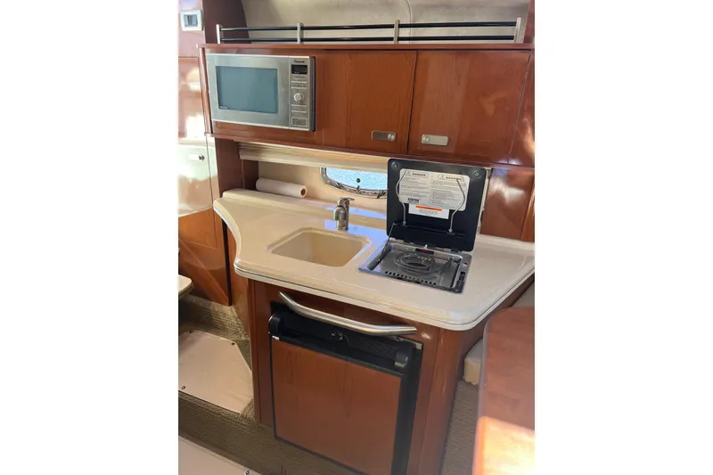 Slide: The Image of Compact kitchen area in 2013 Sea Ray Sundancer 280 with microwave, sink, and stove. - 20
