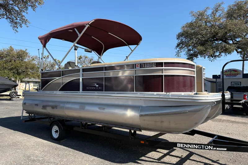 Slide: The Image of 2016 Bennington 21 SLX pontoon boat on trailer, featuring maroon and silver design. - 3
