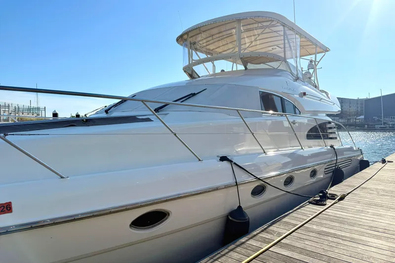 Slide: The Image of Luxury Fairline Squadron 55 yacht from 2000 docked at marina under clear blue sky. - 2