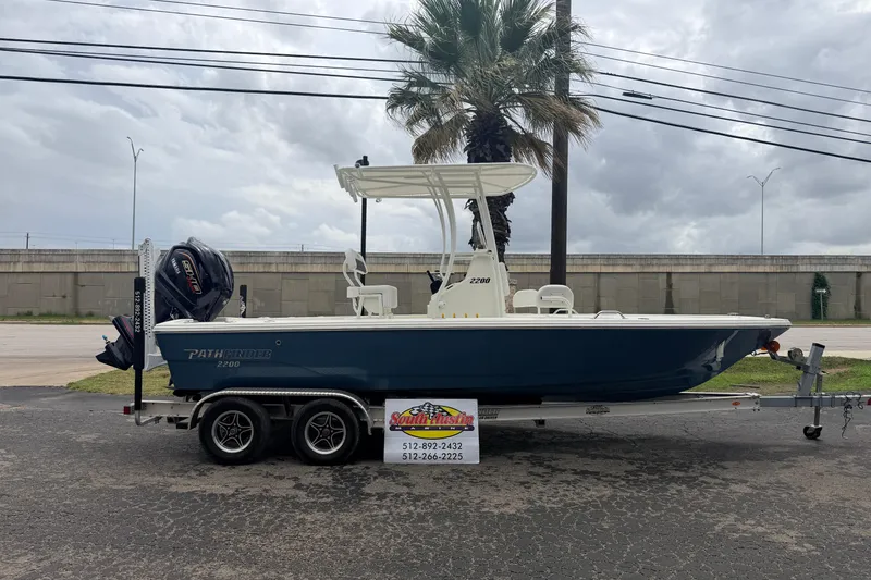 Slide: The Image of 2026 Pathfinder 2200 TRS boat on trailer, parked outdoors under cloudy sky. - 2