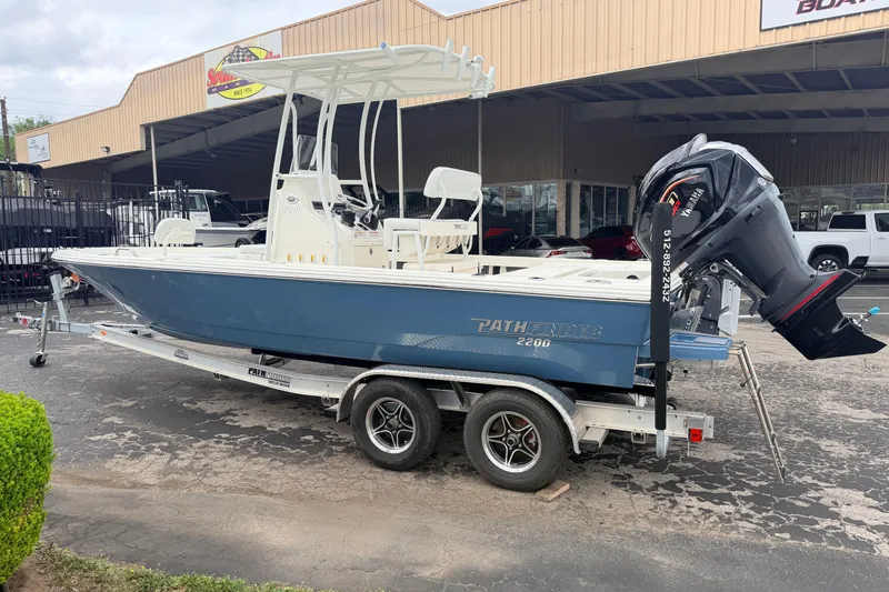 Slide: The Image of 2026 Pathfinder 2200 TRS boat on trailer, displayed outside dealership. - 57