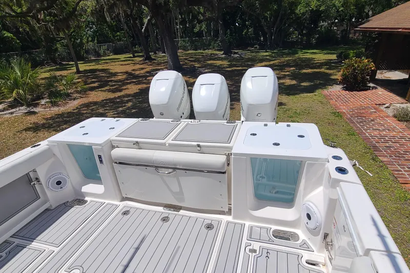 Slide: The Image of 2022 Sea Fox 368 Commander boat deck with triple outboard engines, surrounded by lush greenery. - 6