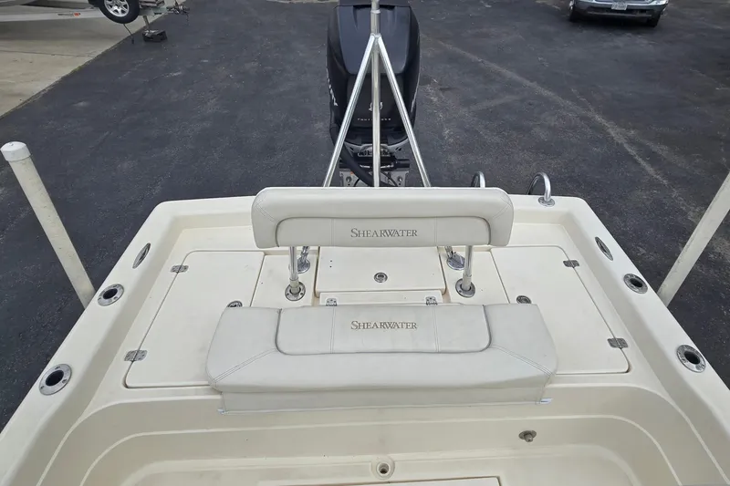 Slide: The Image of 2006 ShearWater 2400Z boat deck with seating and motor, parked on asphalt. - 15