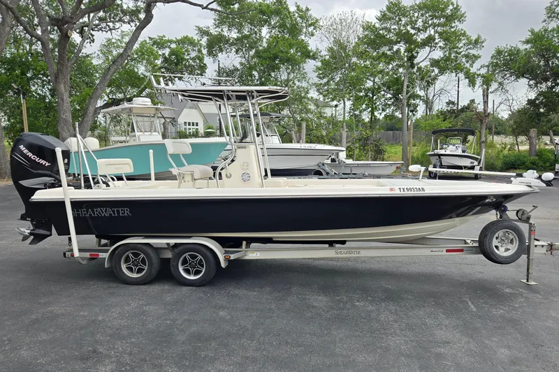 Slide: The Image of 2006 ShearWater 2400Z boat on trailer, parked outdoors with trees in the background. - 2