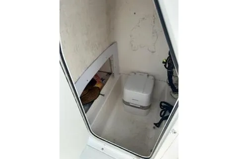 Slide: The Image of 2006 Sea Hunt Triton 220 boat interior with storage compartment and portable toilet. - 22