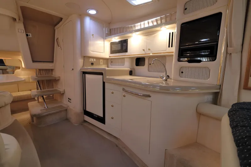 Slide: The Image of Interior of a 2000 Sea Ray 340 Sundancer yacht, featuring a compact kitchen area. - 19